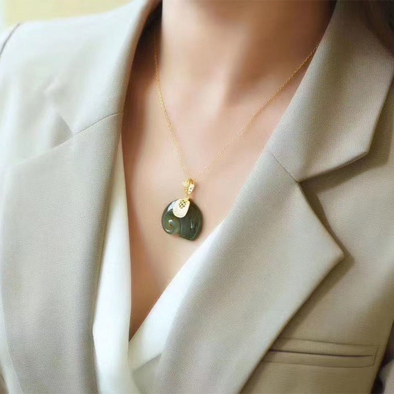 Collier pendentif jade blanc doré porté sur veste beige – bijou symbolique cadeau femme 