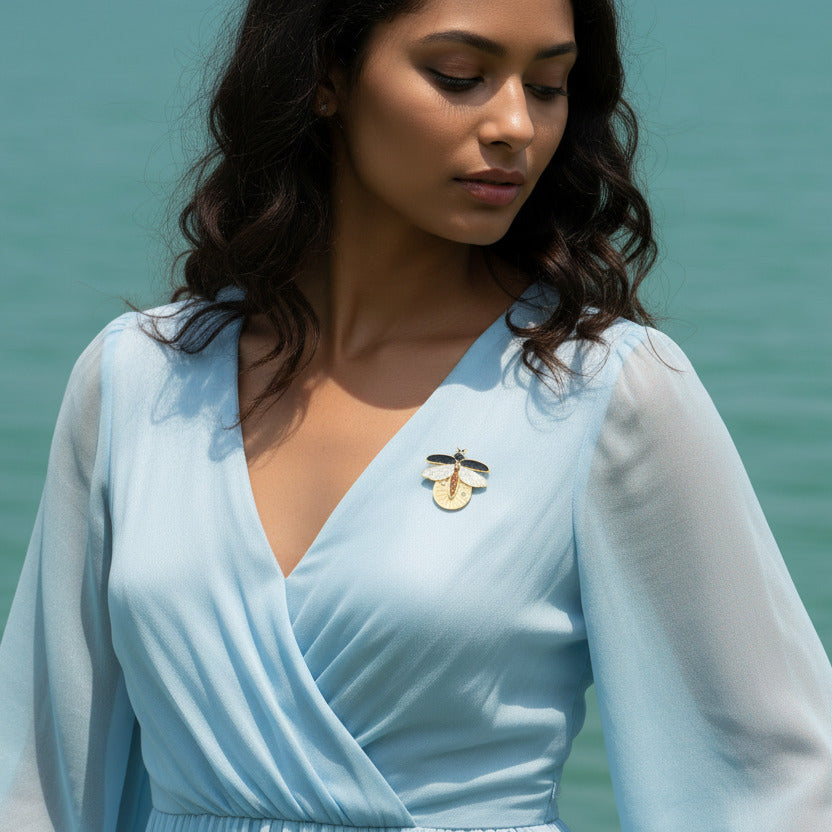 Femme portant la broche luciole dorée sur robe bleue — bijou symbolique porté sur le décolleté, style élégant et nature