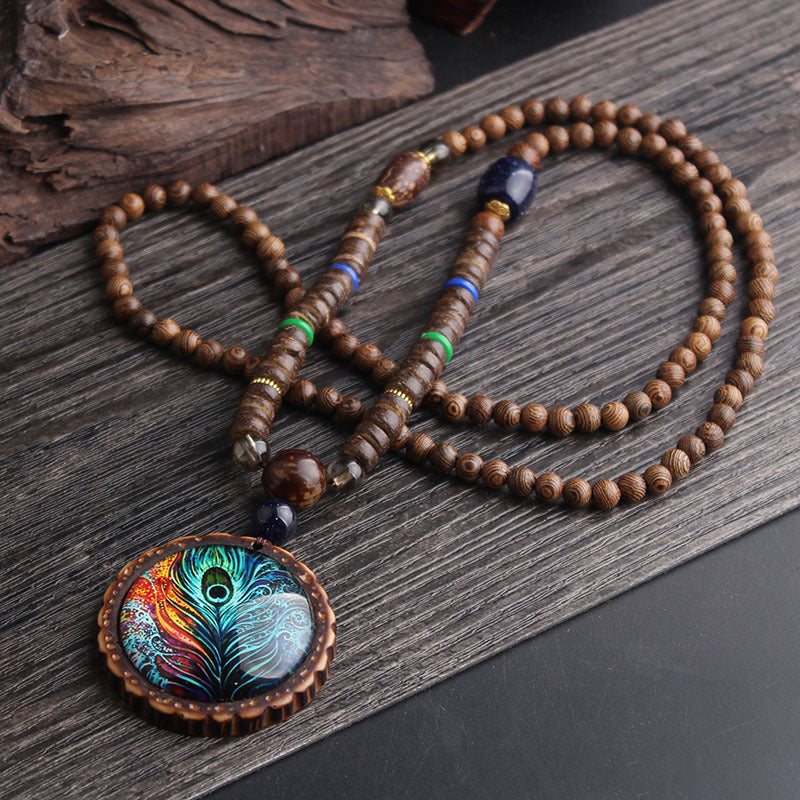 Collier sautoir ethnique bohème avec pendentif plume de paon irisé – vue d'ensemble sur fond sombre