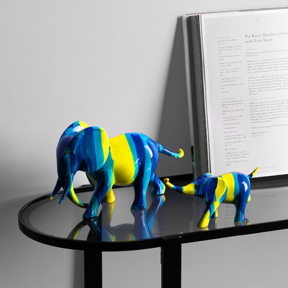 Duo mère et petit éléphant résine bleu jaune — petite trompe du petit tenant la queue de la mère, posés sur table console