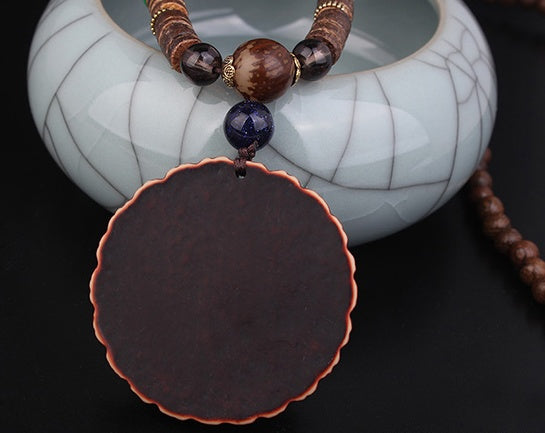 Collier bohème plume de paon sur surface en bois – vue de la chaîne de perles et du médaillon coloré - face arrière