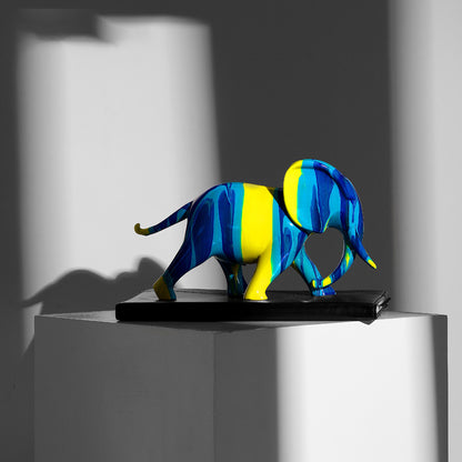 Sculpture éléphant résine bleu jaune sur socle — vue artistique avec ombres, ornement décoratif contemporain