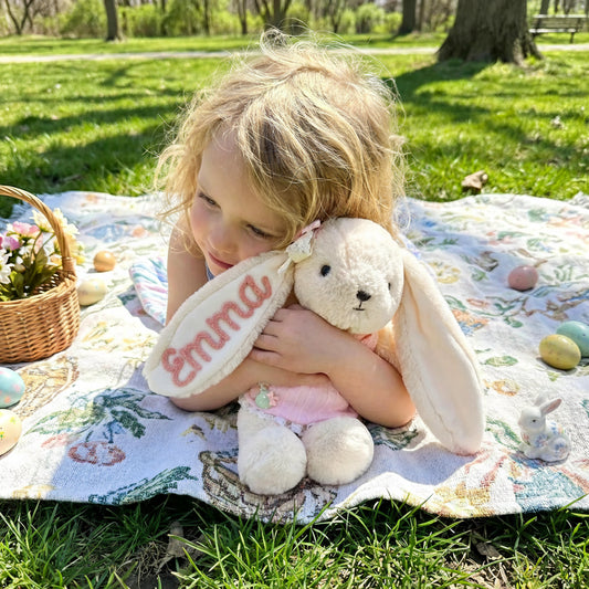 Enfant câlinant une peluche lapin personnalisée avec prénom brodé Amelia, idée cadeau naissance mignonne.
